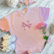 A pink t-shirt romper for babies in size 6-9 months. This is pink and purple. The T-Shirt is personalised with 'Nancy'.