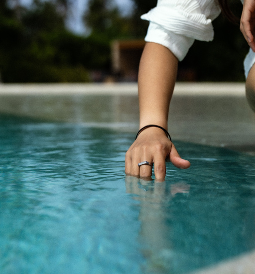 man dipping hand in pool with signet ring and cuff bracelet to show water redistance of jewellery 