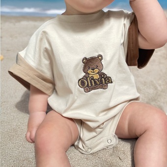 Baby wearing a beige and brown t-shirt romper. The T-shirt is personalised with a teddy bear design.