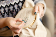 Image shows someone embroidering a flower onto a tote bag using our beginner hand sewing craft kit with stick and stitch templates. 