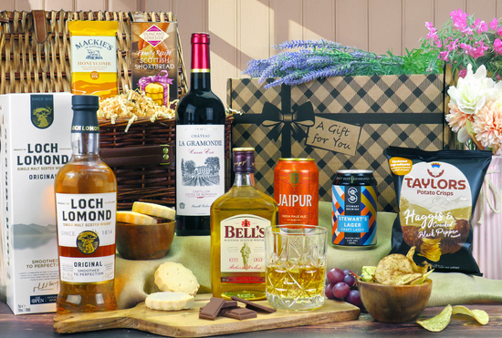Gift hampers with bottles of red wine, whisky and cans of beer, along with crisps, chocolate and shortbread