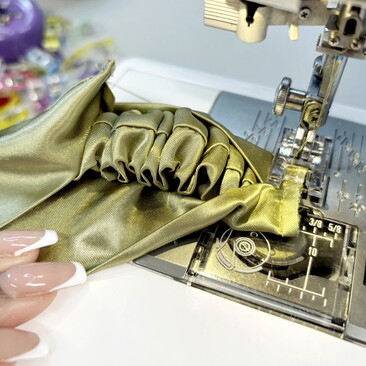 green satin fabric on sewing machine close up