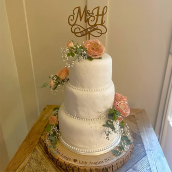 wedding cake sitting on a personalised cake stand made from a real slice of wood and personalised with engraving of the couple's name and wedding date
